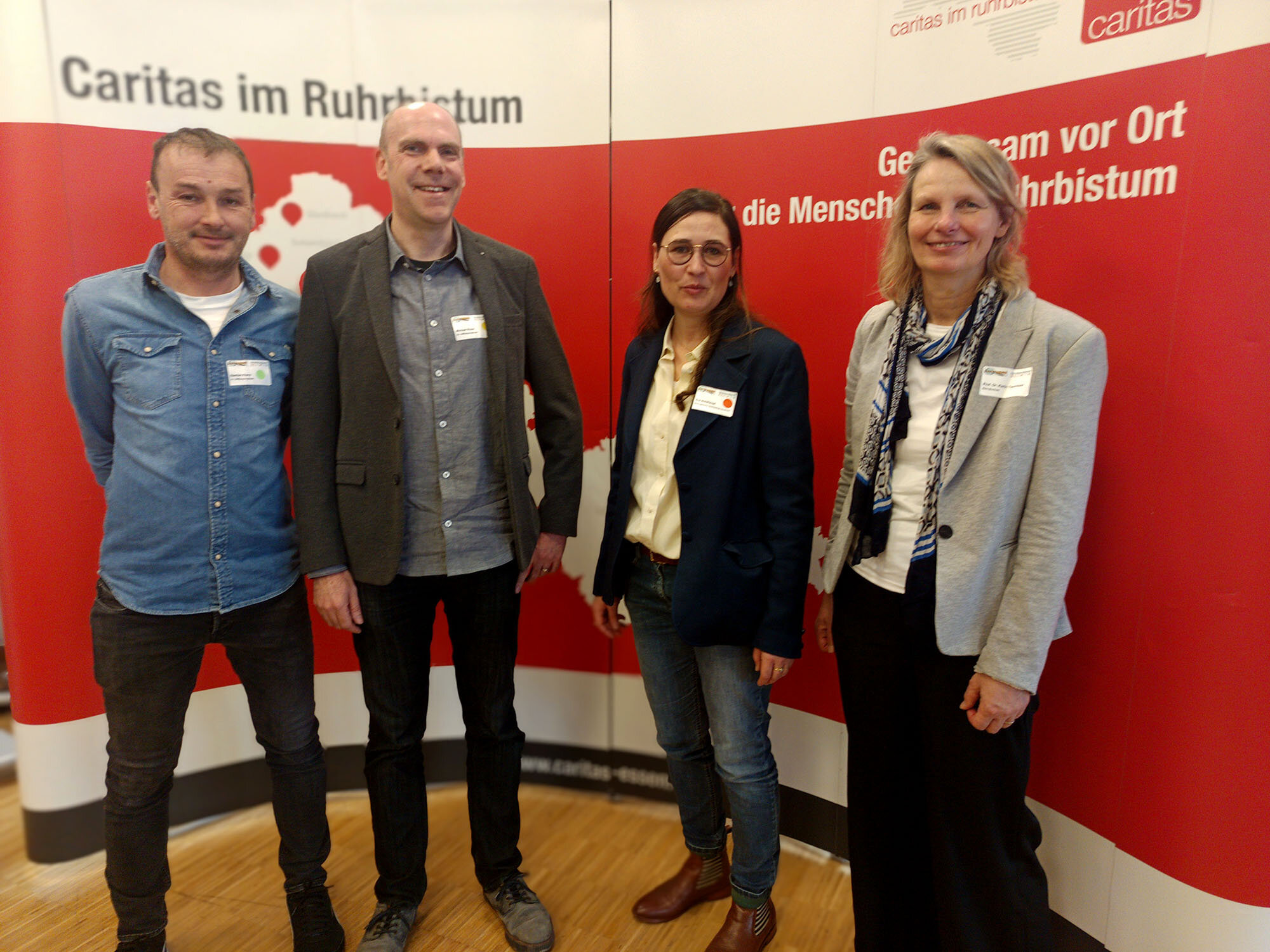 Vier Personen stehen vor einer Stellwand.